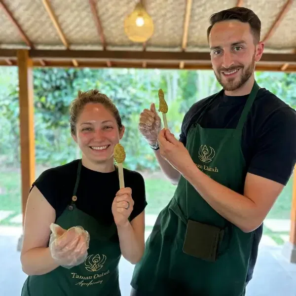 a couple showing the satay lilit they made during balinese cooking class in Ubud