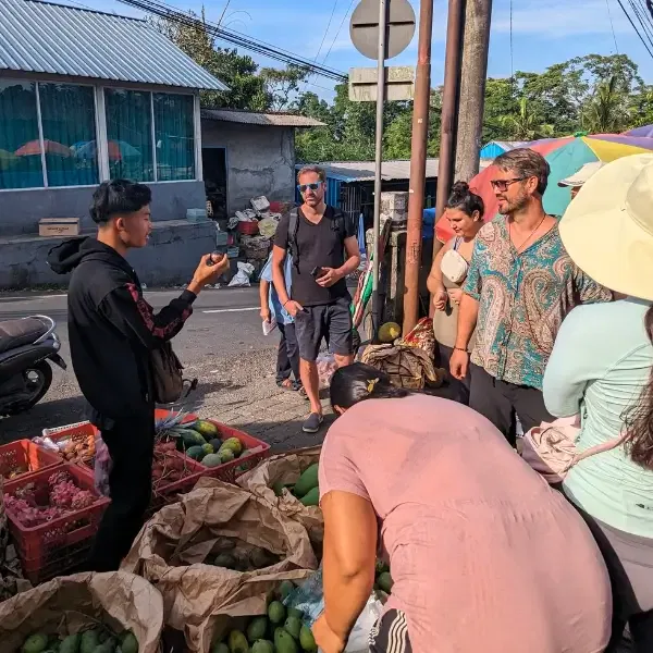 a cooking instructor explaining about fruit in Bali to the travelers in the market