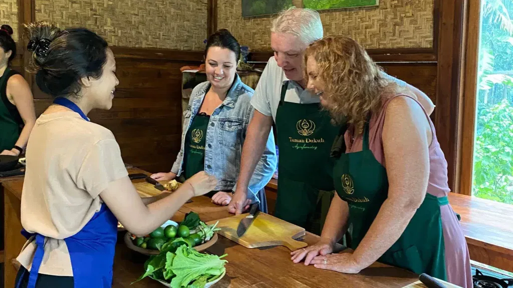 Guests enjoying a hands-on Evening Bali Cooking Class in a peaceful open-air kitchen.