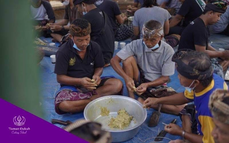 Balinese community members engaged in Gotong Royong (communal work), preparing traditional dishes together in a Paon for a ceremony.