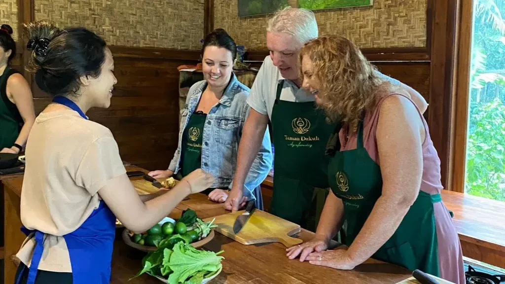Guests enjoying a hands-on Evening Bali Cooking Class in a peaceful open-air kitchen.